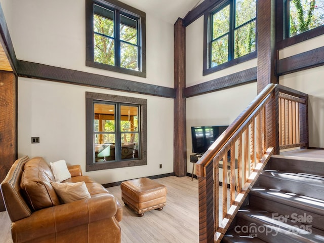 living room with plenty of natural light, wood finished floors, and a towering ceiling