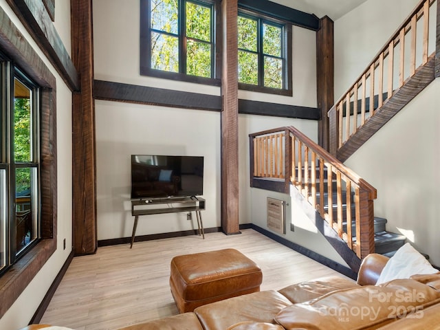 living room featuring a wealth of natural light, a high ceiling, baseboards, and wood finished floors