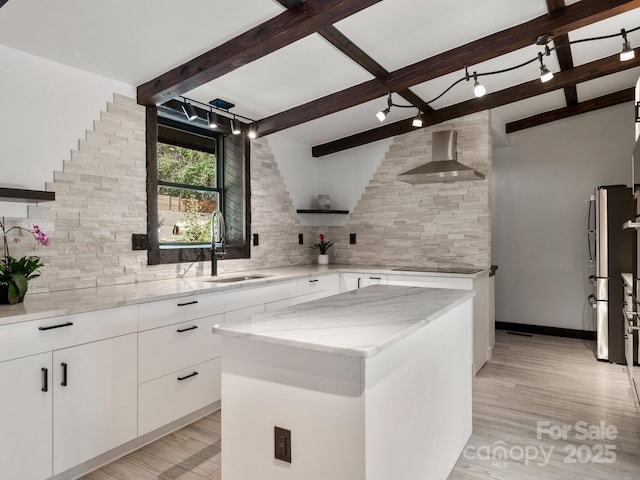 kitchen with a sink, wall chimney range hood, decorative backsplash, light stone countertops, and beamed ceiling