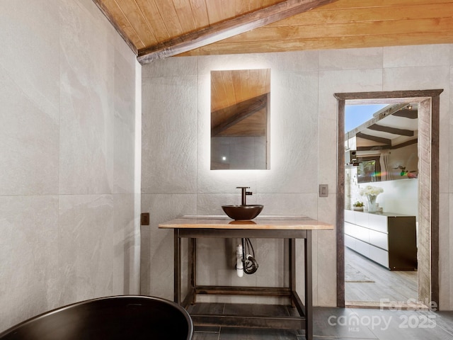 bathroom with vaulted ceiling with beams, wood ceiling, and a sink