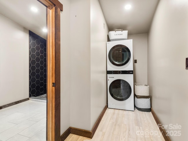 washroom featuring light wood-type flooring, recessed lighting, stacked washer / dryer, baseboards, and laundry area