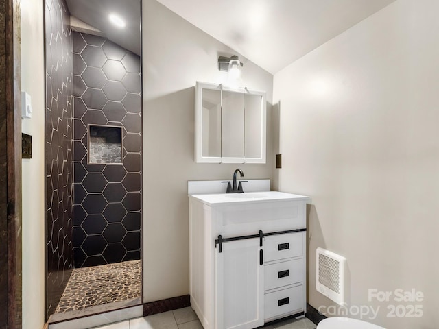 full bathroom with visible vents, tiled shower, tile patterned flooring, vaulted ceiling, and vanity