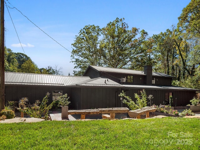 back of house featuring metal roof, a lawn, and board and batten siding