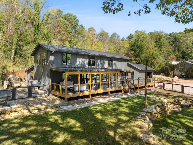 rear view of property with a lawn, a gate, metal roof, fence, and a wooden deck