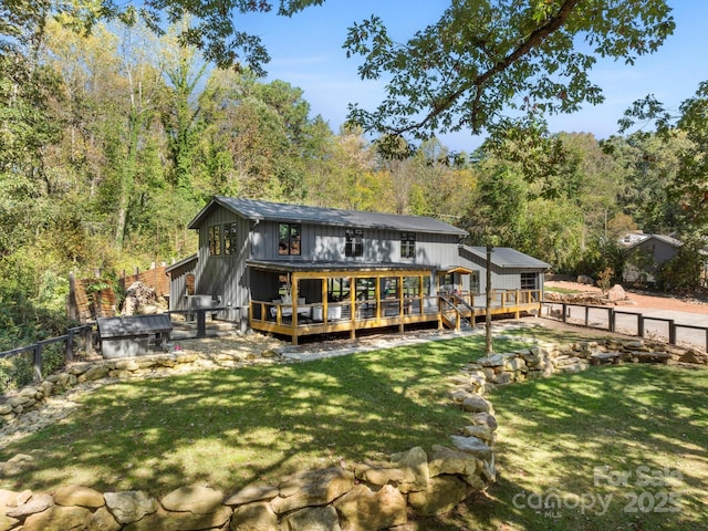 back of property with a fenced backyard, a yard, a deck, and a forest view