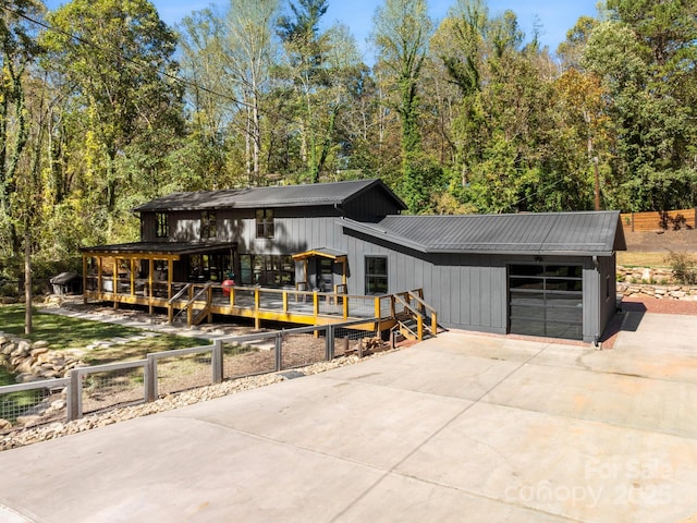 view of front of home with concrete driveway, an attached garage, fence, and metal roof