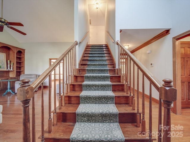 stairs featuring ceiling fan, high vaulted ceiling, and hardwood / wood-style floors