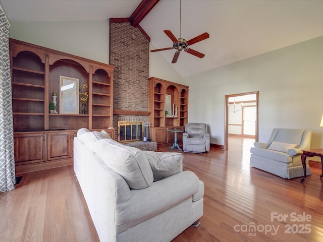 living room featuring a brick fireplace, beam ceiling, high vaulted ceiling, and light wood-type flooring