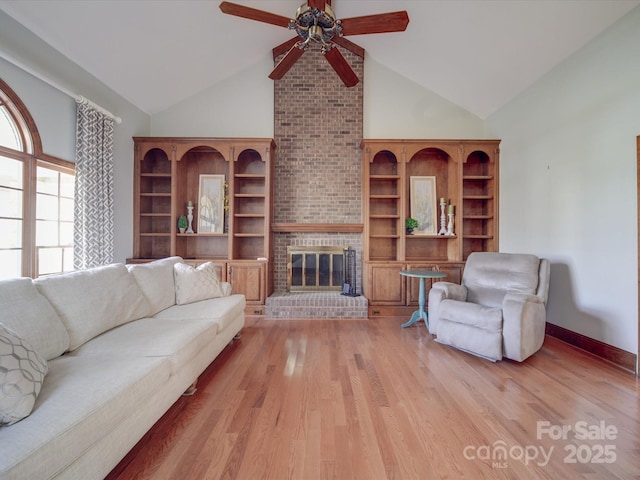 living room featuring a fireplace, high vaulted ceiling, ceiling fan, and light wood-type flooring