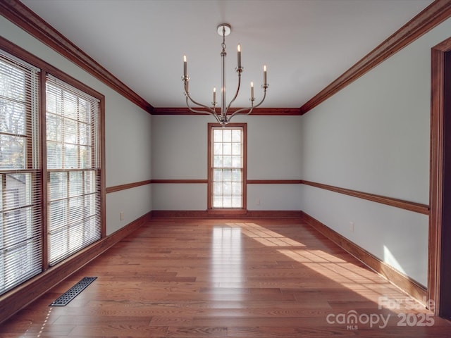 spare room with crown molding, a notable chandelier, and light hardwood / wood-style floors