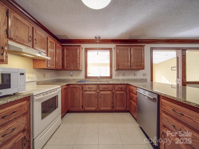 kitchen with sink, hanging light fixtures, light tile patterned floors, white appliances, and a textured ceiling