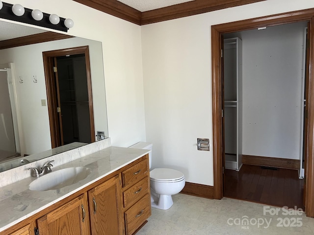 bathroom featuring ornamental molding, toilet, vanity, and a shower