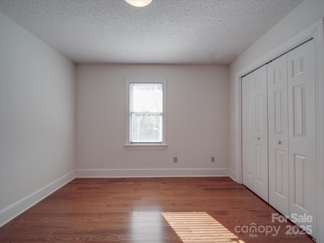 unfurnished bedroom with hardwood / wood-style flooring, a closet, and a textured ceiling