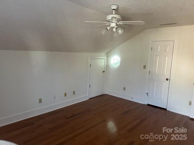 additional living space with lofted ceiling, ceiling fan, dark hardwood / wood-style floors, and a textured ceiling