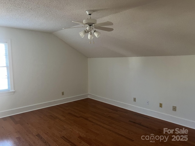 additional living space featuring lofted ceiling, ceiling fan, dark wood-type flooring, and a textured ceiling