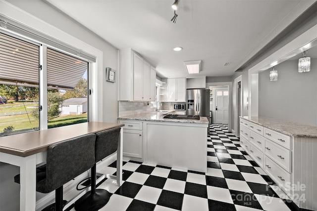 kitchen featuring decorative backsplash, sink, white cabinets, pendant lighting, and appliances with stainless steel finishes