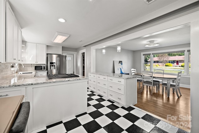 kitchen with kitchen peninsula, stainless steel appliances, sink, white cabinetry, and dark hardwood / wood-style flooring