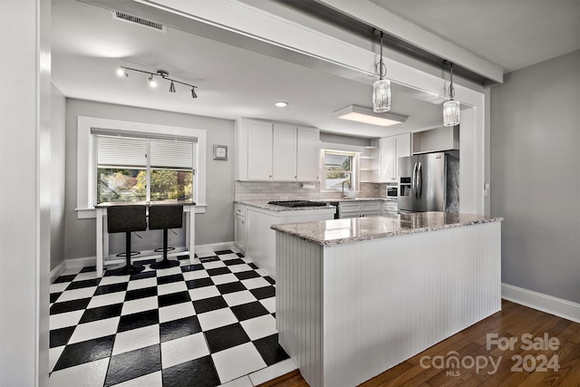 kitchen with pendant lighting, white cabinets, light stone counters, decorative backsplash, and stainless steel fridge with ice dispenser