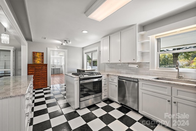 kitchen with appliances with stainless steel finishes, white cabinetry, sink, and a wealth of natural light