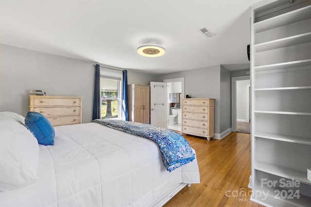 bedroom featuring ensuite bath and hardwood / wood-style floors