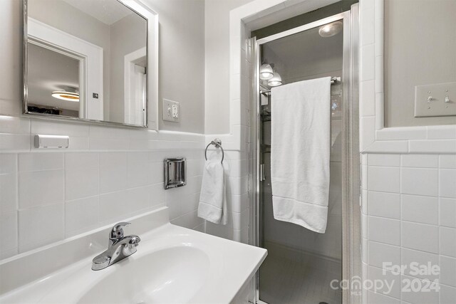 bathroom featuring vanity, tile walls, and walk in shower