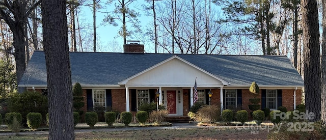 view of front of house featuring a shingled roof, a chimney, and brick siding