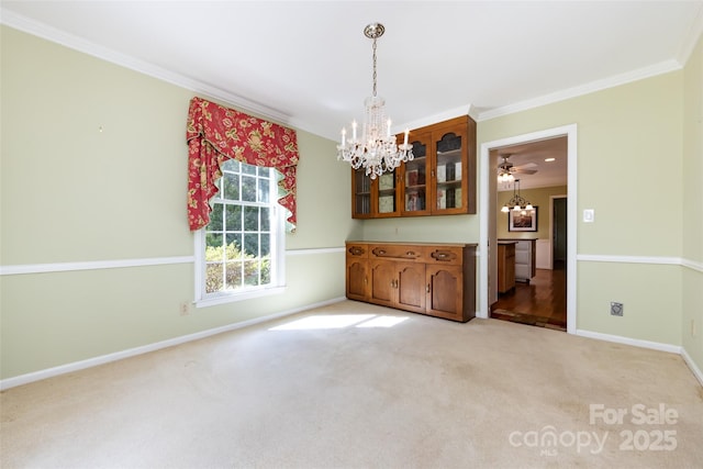 unfurnished dining area with crown molding, baseboards, light colored carpet, and a notable chandelier