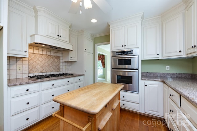 kitchen with stainless steel appliances, white cabinets, decorative backsplash, and dark wood-type flooring