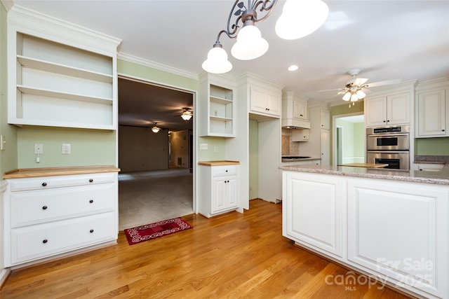 kitchen with double oven, pendant lighting, white cabinets, and ceiling fan