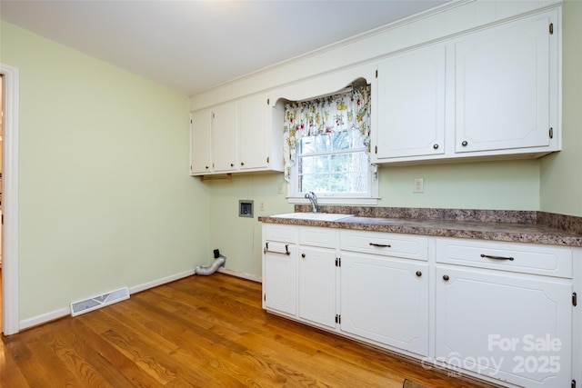 laundry area featuring cabinet space, light wood finished floors, visible vents, hookup for a washing machine, and a sink