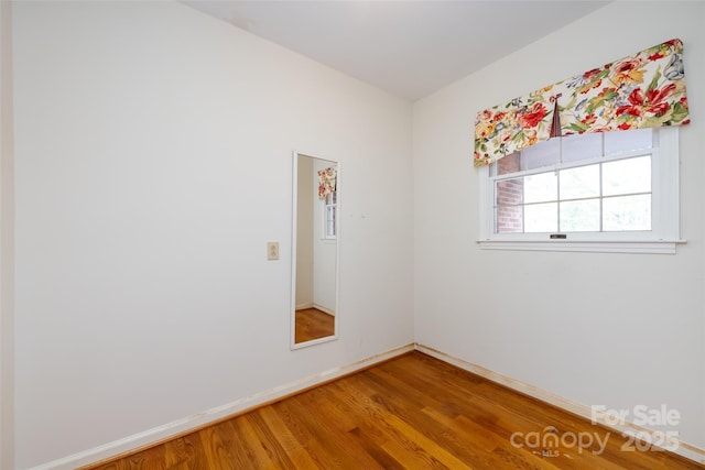 empty room featuring wood finished floors and baseboards