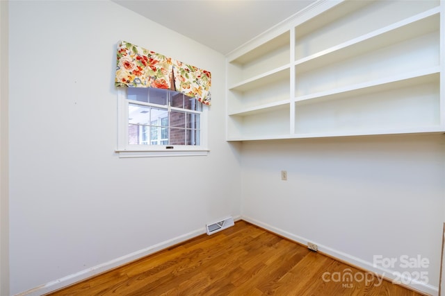 spare room with visible vents, baseboards, and wood finished floors