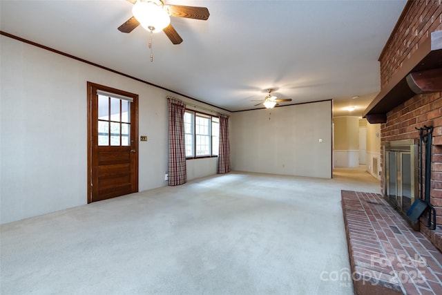 unfurnished living room with crown molding, light carpet, a fireplace, and ceiling fan