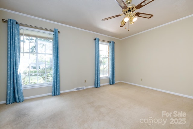 spare room featuring light carpet, visible vents, baseboards, a ceiling fan, and ornamental molding