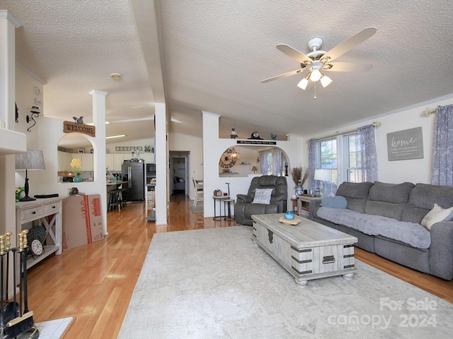 living room featuring light hardwood / wood-style floors, lofted ceiling with beams, a textured ceiling, and ceiling fan