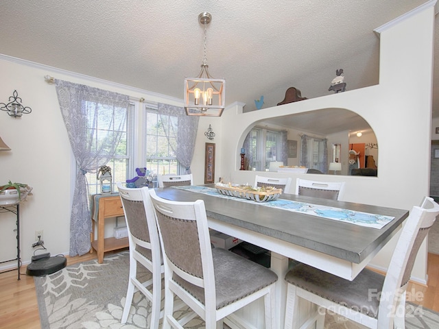 dining space featuring light wood-type flooring, an inviting chandelier, and a textured ceiling