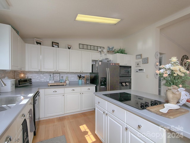 kitchen with tasteful backsplash, black appliances, light hardwood / wood-style flooring, and white cabinets