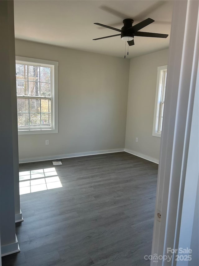 empty room featuring dark wood finished floors, baseboards, and ceiling fan