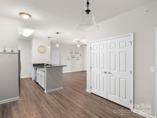 kitchen featuring dark wood-type flooring, decorative light fixtures, stainless steel appliances, kitchen peninsula, and white cabinets