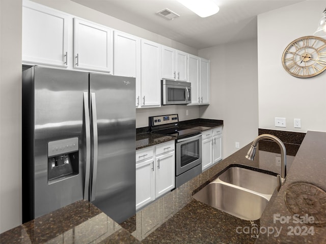 kitchen featuring dark stone countertops, sink, stainless steel appliances, and white cabinets