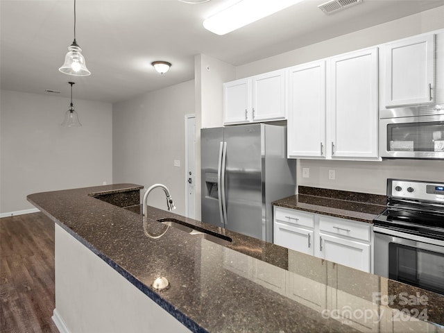 kitchen with pendant lighting, dark wood-type flooring, dark stone countertops, appliances with stainless steel finishes, and white cabinetry