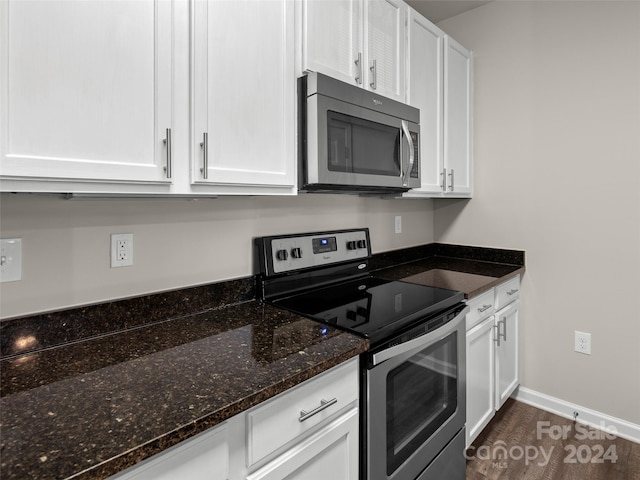 kitchen featuring appliances with stainless steel finishes, dark stone counters, and white cabinetry