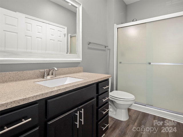 bathroom with walk in shower, hardwood / wood-style flooring, vanity, and toilet