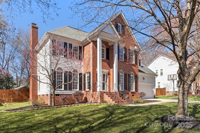 greek revival inspired property featuring a garage, brick siding, fence, a front lawn, and a chimney