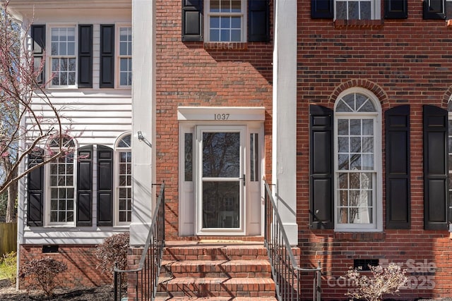 view of exterior entry featuring crawl space and brick siding