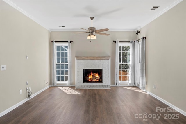 unfurnished living room with baseboards, visible vents, wood finished floors, crown molding, and a brick fireplace