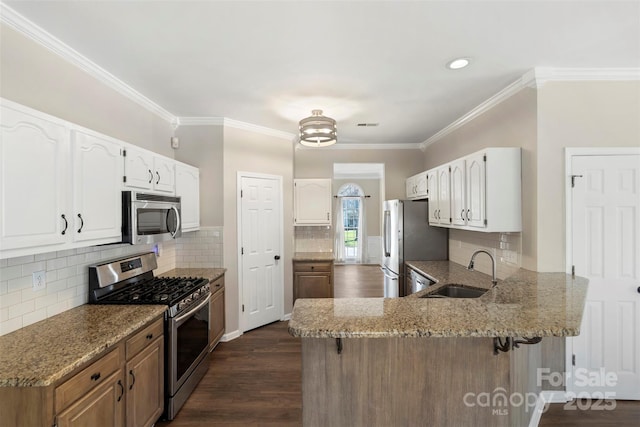 kitchen with stainless steel appliances, a sink, a peninsula, and light stone counters