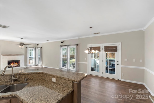 kitchen with dark wood finished floors, a fireplace, visible vents, open floor plan, and a sink