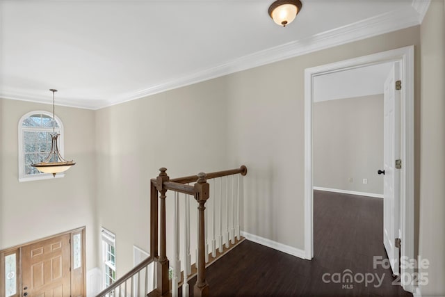 hallway with dark wood-style floors, baseboards, ornamental molding, and an upstairs landing