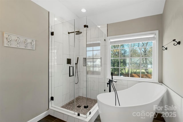 full bathroom featuring a stall shower, a freestanding bath, and baseboards